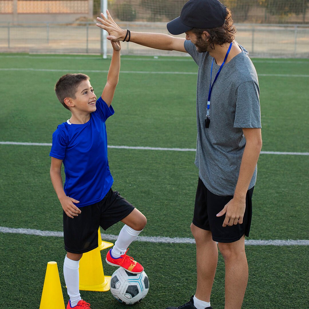 football-trainer-congratulating-kid-side-view